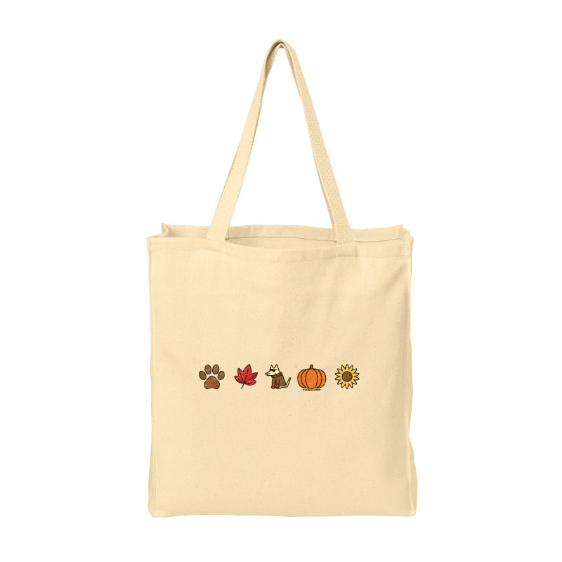 A natural beige canvas tote bag with two shoulder straps, featuring a horizontal row of small autumn-themed illustrations on the front: a paw print, a red maple leaf, a dog, a pumpkin, and a sunflower.