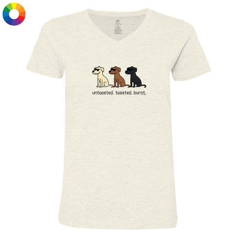 A women's short-sleeve V-neck t-shirt in a light heathered cream color, featuring a graphic of three dogs (Beagle, Labrador, and Rottweiler) with the text 'untoasted, toasted, burnt.' underneath.