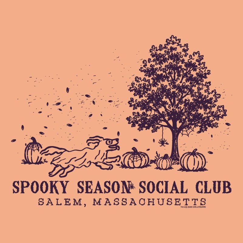 A peach-colored graphic print featuring a dark purple illustration of a running dog, pumpkins, a tree, and falling leaves, with the text 'SPOOKY SEASON SOCIAL CLUB' and 'SALEM, MASSACHUSETTS' below.